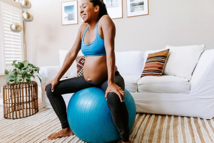 This may contain: a pregnant woman sitting on an exercise ball