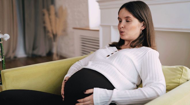 This may contain: a pregnant woman sitting on a yellow couch
